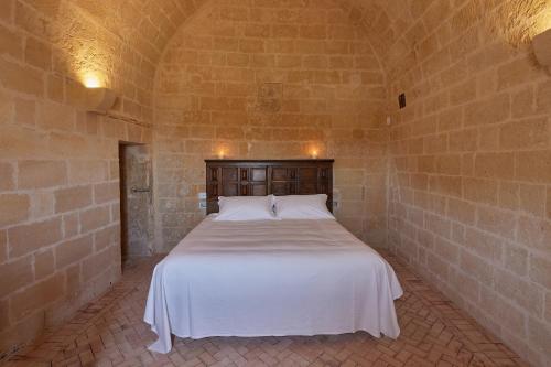 a bedroom with a white bed in a brick wall at Sextantio Le Grotte Della Civita in Matera