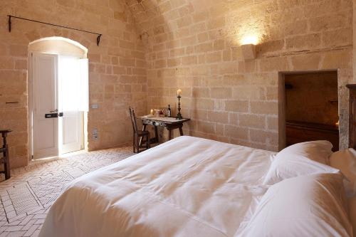 a bedroom with a large white bed and a table at Sextantio Le Grotte Della Civita in Matera