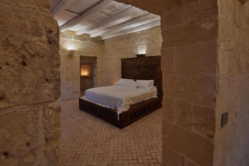 a bedroom with a bed in a stone wall at Sextantio Le Grotte Della Civita in Matera