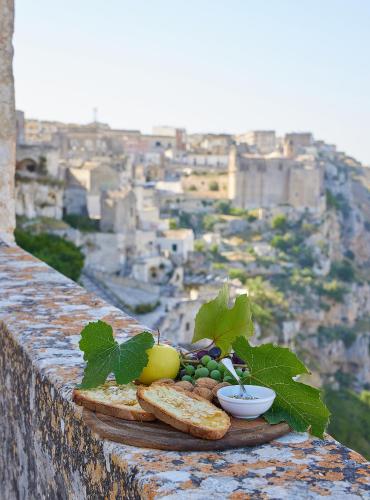 a plate of bread and fruit on a ledge with a view at Sextantio Le Grotte Della Civita in Matera