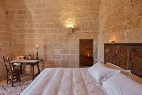 a bedroom with a white bed and a table with a tableasonable at Sextantio Le Grotte Della Civita in Matera