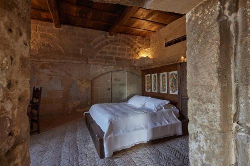 a bedroom with a bed in a stone wall at Sextantio Le Grotte Della Civita in Matera