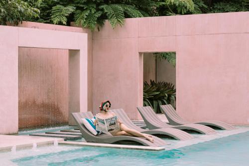 a woman sitting in a chair next to a swimming pool at SYN Boutique Hotel in Chiang Mai