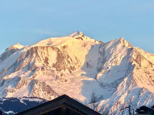 una montaña cubierta de nieve frente a un edificio en Chalet Les Rhodos, en Cordon