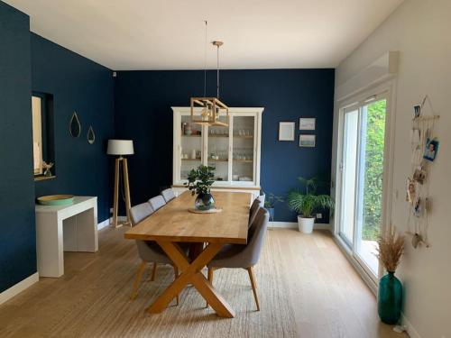 ein Esszimmer mit einem Tisch und einer blauen Wand in der Unterkunft JO 2024 Maison avec jardin proche Paris Versailles in Saclay