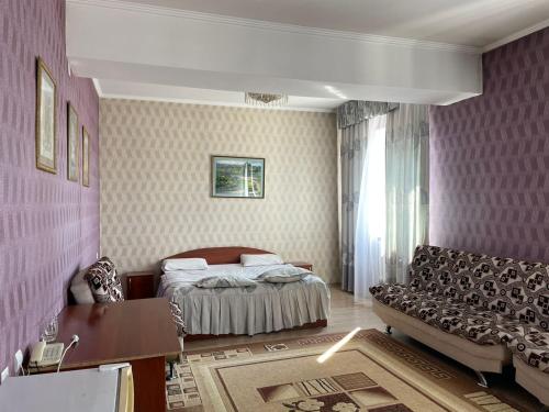 a bedroom with a bed and a couch at Гостиничный комплекс Жеты Казына in Zharkent