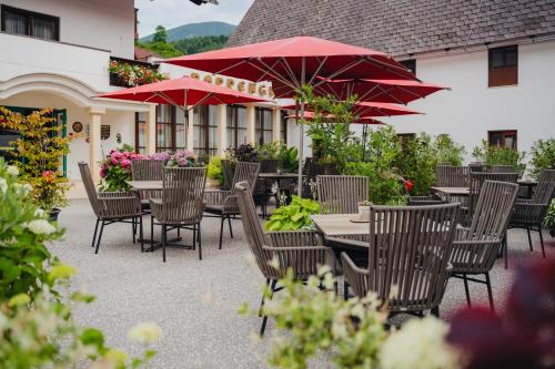 an outdoor patio with tables and chairs with red umbrellas at Relax- & Wanderhotel Poppengut in Hinterstoder