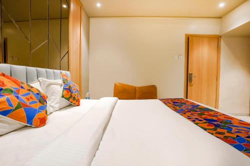 a bedroom with a large white bed with colorful pillows at FabHotel Springs Lodging in Mire