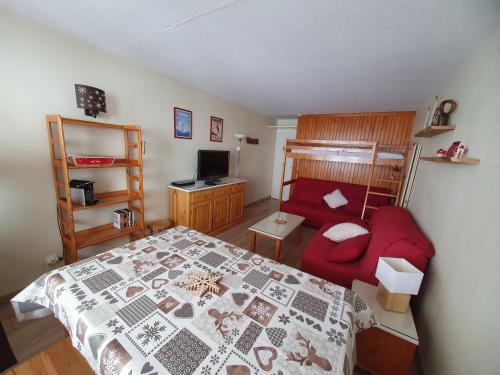 1 dormitorio con 1 cama y 1 sofá rojo en La Mongie, Studio pieds des pistes, parking intérieur privé, en La Mongie