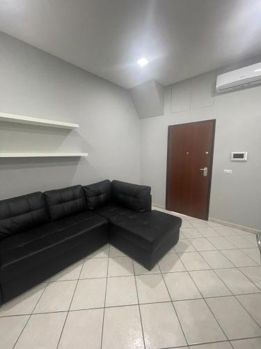- un canapé noir dans une chambre avec porte dans l'établissement La perla di Napoli e della Costiera, à San Vitaliano 
