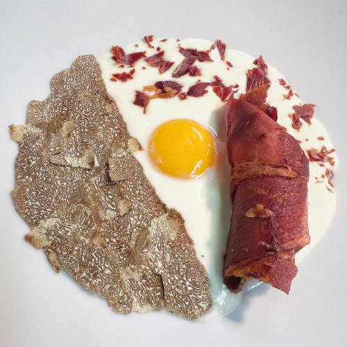 a fried egg and bacon on a white plate at Il Castello di Bubbio in Bubbio