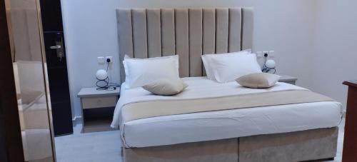 a bedroom with a large bed with white sheets and pillows at العلي للشقق المخدومة Alalihotel in Hafr Al Baten