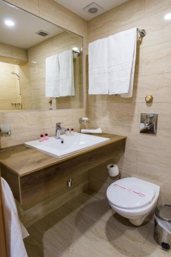 a bathroom with a sink and a toilet and towels at Grand Hotel Sunny Beach - All Inclusive in Sunny Beach