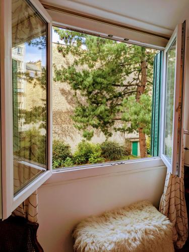 - un siège de fenêtre dans une chambre avec vue sur un arbre dans l'établissement Appartement avec balcon proche de Montmartre, à Paris
