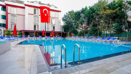 a large swimming pool with blue chairs and a building at Gardan Hotel in Beylikduzu