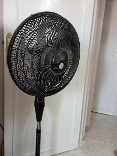 a black fan on a stand next to a wall at Holiday Inn fayoum in Kafr Maḩfūz̧