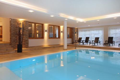AvenidA Mountain Resort by Alpin Rentals في كابرون: مسبح في الفندق مع الكراسي والطاولات
