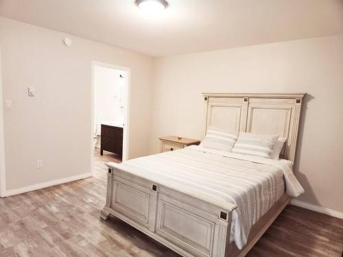 a white bedroom with a large bed with white sheets at Comfort First - sleeps 6 in Whitehorse