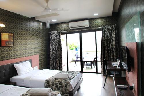 a hotel room with two beds and a television at Hotel Pearls in Aurangabad