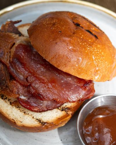 a bacon sandwich on a plate with a tablespoon of sauce at Kew Gardens Hotel in Kew