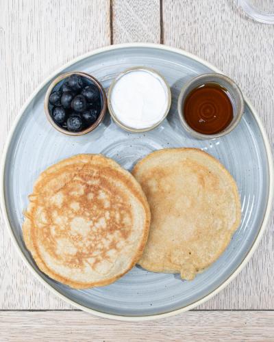 a plate with pancakes and syrup and blueberries on a table at Kew Gardens Hotel in Kew