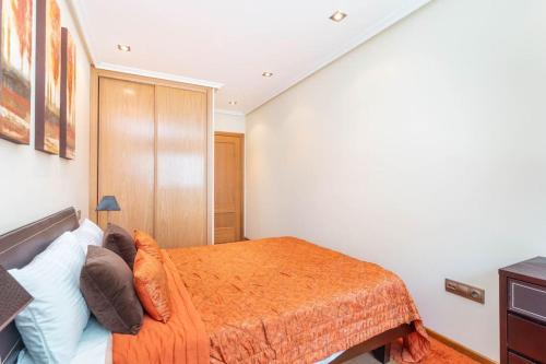 1 dormitorio con 1 cama con manta naranja en Apartamento con garaje, en Luanco