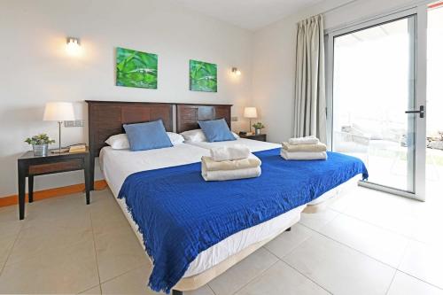 1 dormitorio con 1 cama grande con sábanas azules y blancas en Salobre Vista Golf 1 en Maspalomas