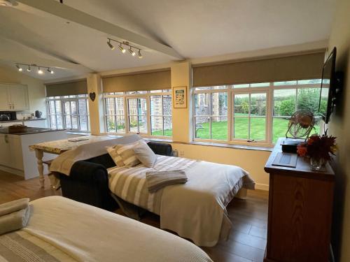1 dormitorio con 2 camas, mesa y ventanas en Tegfan Garden Suite en Talgarth