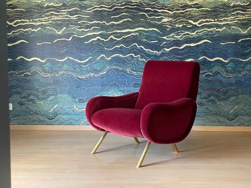 a red chair sitting in a room with a painting at Deluxe Apartment Vittorio Po Torino centro in Turin