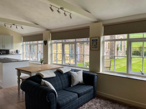 a living room with a couch and a table and windows at Tegfan Garden Suite in Talgarth