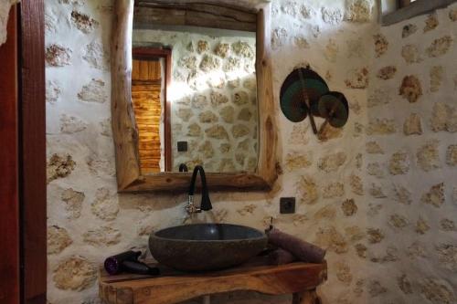 uma casa de banho com um lavatório de pedra e um espelho. em Alma Villa 2 - Lovely 1 Bedroom with Pool em Uluwatu