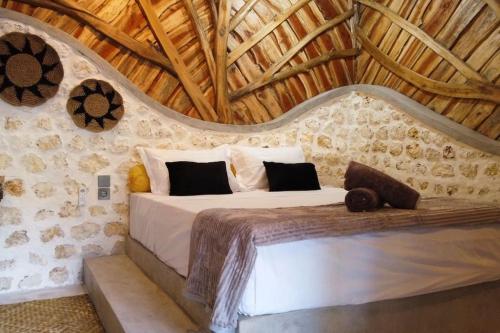 um quarto com uma cama numa parede de pedra em Alma Villa 2 - Lovely 1 Bedroom with Pool em Uluwatu