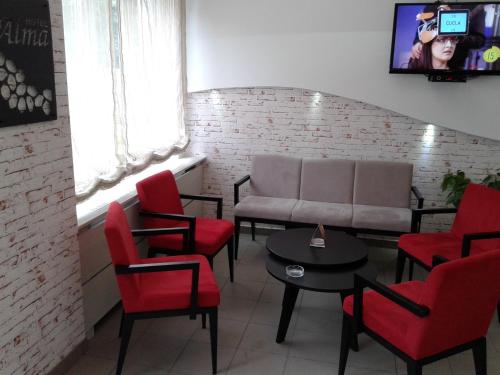 a waiting room with a couch and red chairs at Garni hotel Alma in Pirot