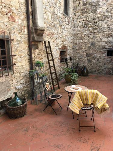 eine Terrasse mit einem Tisch, Stühlen und einer Ziegelwand in der Unterkunft MEA CASA Toscana in Castellina in Chianti