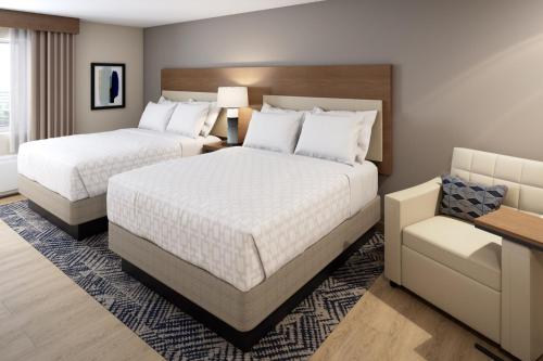 una habitación de hotel con 2 camas y una silla en Candlewood Suites Jackson, en Locust Grove