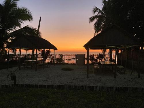 een zonsondergang op het strand met tafels en parasols bij Hotel et Restaurant Chez Tasmine 