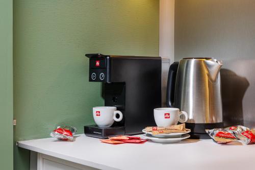 uma cafeteira e duas chávenas de café num balcão em Aries' Collection Luxury Suites em Braşov
