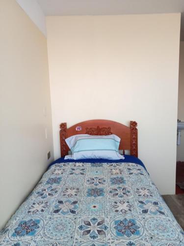 een slaapkamer met een bed met een blauwe en witte quilt bij La casa de Yllari in Cuzco