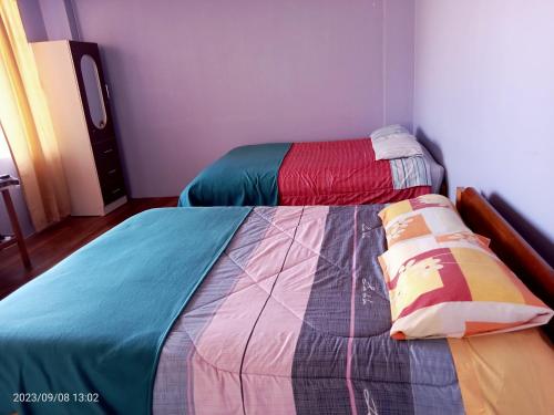 een slaapkamer met 2 bedden en kleurrijke dekens bij La casa de Yllari in Cuzco