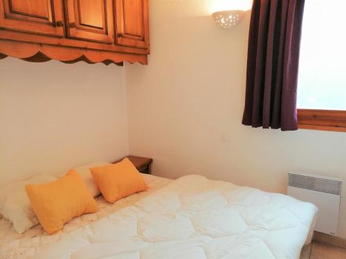 モリヨンにあるAppartement Morillon 1100, 3 pièces, 6 personnes - FR-1-412-17のベッドルーム1室(白いベッド1台、オレンジ色の枕2つ付)
