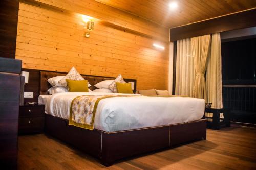 a bedroom with a large bed with a wooden wall at Oro Montana Hotels and Resort in Bhurtuk