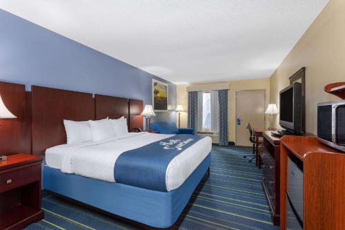 a hotel room with a bed and a flat screen tv at Days Inn by Wyndham Chipley in Chipley