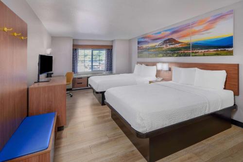 Habitación de hotel con 2 camas y TV de pantalla plana. en Days Inn & Suites by Wyndham Greeley en Greeley