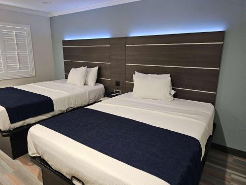 a hotel room with two beds and a headboard at Travelodge Inn & Suites by Wyndham Fullerton in Fullerton