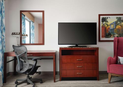 a room with a desk with a television and a chair at Hilton Garden Inn Ann Arbor in Ann Arbor