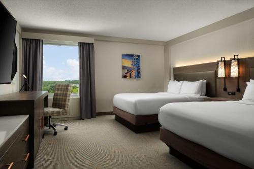 um quarto de hotel com duas camas e uma secretária e uma janela em DoubleTree by Hilton Pittsburgh Airport em Moon Township