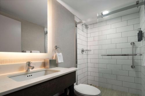 a bathroom with a sink and a toilet and a mirror at DoubleTree by Hilton Pittsburgh Airport in Moon Township