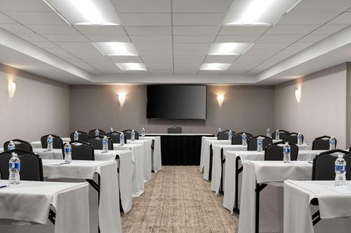 a conference room with tables and chairs and a screen at DoubleTree by Hilton Pittsburgh Airport in Moon Township