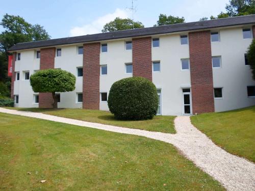 a large white building with a bush in front of it at ibis les Etangs des Moines in Fourmies