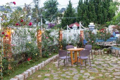 a table and chairs in a garden with a fence at Trà My Villa Đà Lạt BBQ Garden in Da Lat